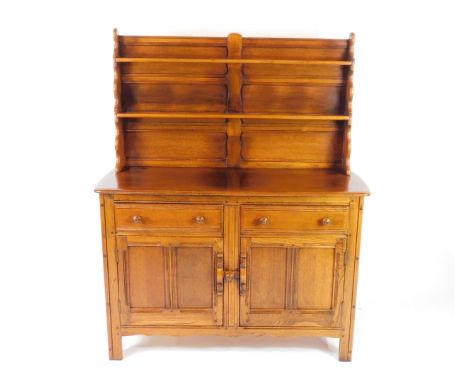 An Ercol elm dresser, waterfall two shelf plate rack, over a pair of frieze drawers above two cupboard doors, secured by a do