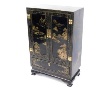 A Chinese gilt decorated ebonised cabinet, the two doors opening to reveal a single shelf, over a frieze drawer, raised on br