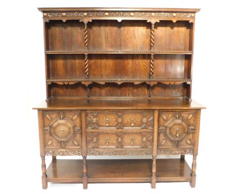 A 17thC style oak dresser, the outswept pediment over a frieze carved with roundels and foliate scrolls, above a two shelf pl
