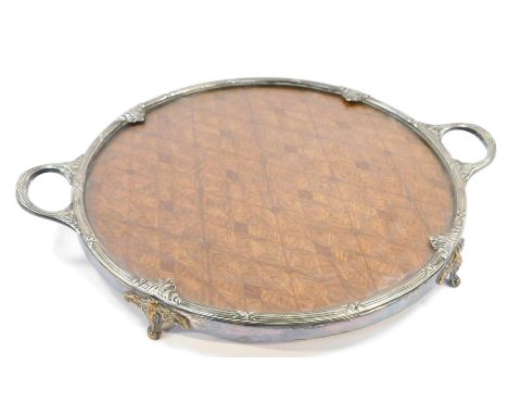 An early 20thC Belgian silver plated circular tray, with a glazed over parquetry central panel, cast with reeding and scrolli
