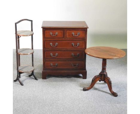 A reproduction bachelor's chest, 62cm wide, together with a three tier folding cake stand and an occasional table, on a tripo