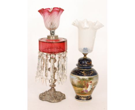 A Victorian drop lustre oil lamp with ruby glass reservoir on plated rococco style base, height 49cm.