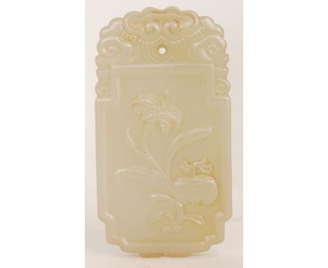 A Chinese celadon jade pendant or plaque,  finely carved in shallow relief with a fruiting branch of peach blossom, the rever