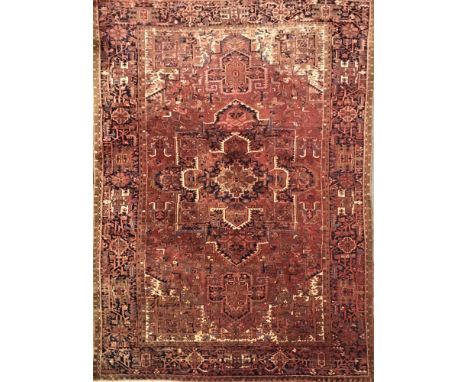 A North West Persian carpet with central red and ivory panel bordered by stylised geometric lozenges, 403cm x 283cm.