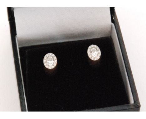 A pair of 18ct white gold diamond cluster earrings, central oval cut diamonds within a round brilliant cut diamond surround, 