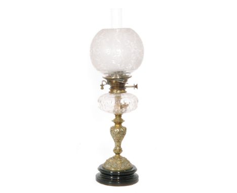 A Victorian brass oil lamp and floral shade with clear glass reservoir on a brass Bacchus mask and acanthus base, height 59cm