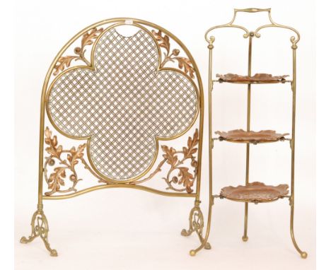 An Edwardian brass arch shaped firescreen with acorn and leaf corner detail and a three tier brass cake stand with pressed co