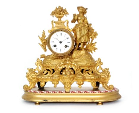 A 19th Century French pressed gilt metal mantle clock mounted with a farm girl holding a rake above a circular dial on scroll
