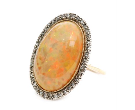 An 18ct gold opal and diamond ring, oval opal within a border of old mine cut diamonds to a plain band, ring size Q