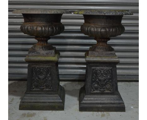 A pair of 19th Century black painted circular cast iron terrace urns of classical form on waisted acanthus panel square plint