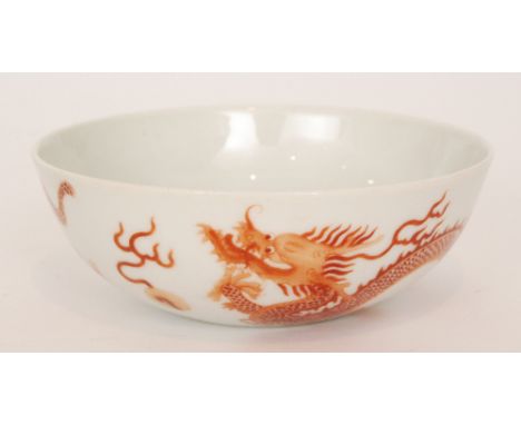 A Chinese shallow bowl decorated to the exterior with two burnt red hand painted dragons chasing two flaming pearls, bears si