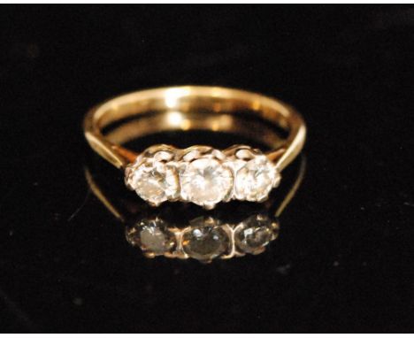 An 18ct three stone diamond ring, central round brilliant cut stone with smaller stone beside, each claw set to a plain taper