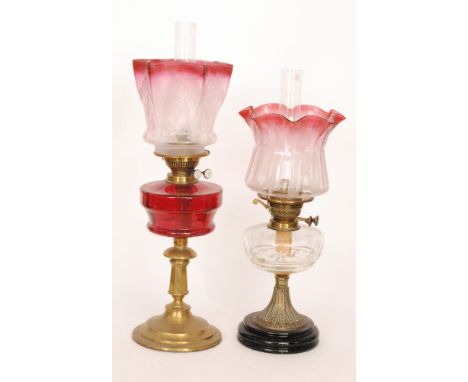 A 20th Century brass oil lamp and shade engraved with urns and swags with ruby reservoir, height 64cm, and a similar oil lamp