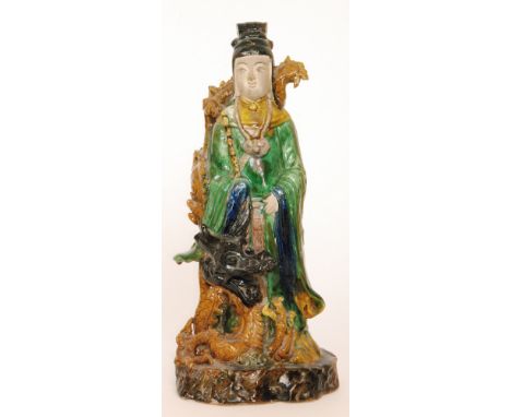 A Chinese porcelain standing figure dressed in green robes with a curled dragon wrapped from the foot to the shoulder, unmark