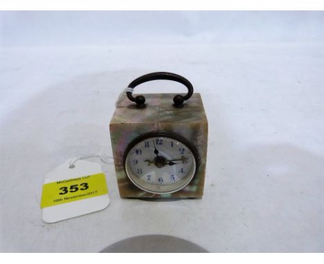 An early 20th century mother-of-pearl travelling alarm clock, the enamel dial with blue Arabic numerals. 2'' high