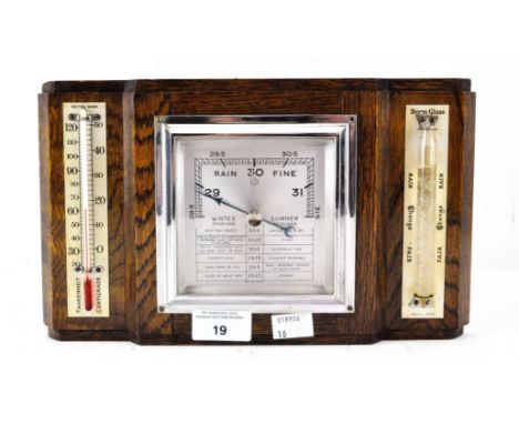 An Art Deco wall hanging oak cased barometer, flanked by a thermometer and storm glass, 17cm x 29cm