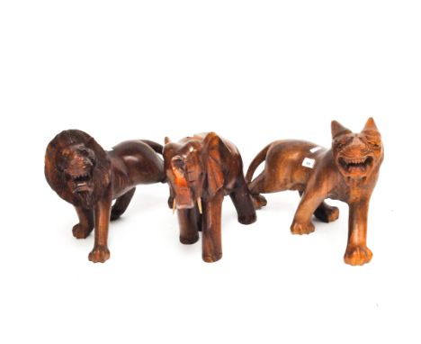 Three large contemporary wood carvings of a roaring tiger, a lion, and an elephant with raised trunk, largest 32cm x 45cm