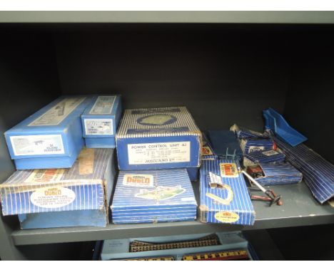 A shelf of Hornby Dublo OO gauge accessories and rolling stock including D1 Through station, D1 Island platform, power unit e