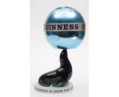 A Carlton Ware Guinness Sealion lamp with revolving shade:, the blue aluminum globe shade with advertising slogan, raised on 