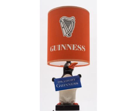 A Carlton Ware 'Draught Guinness' Penguin lamp with shade:, cylindrical orange shade over penguin figure with placard on a sq