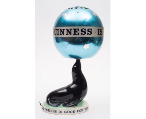 A Carlton Ware Guinness Sealion lamp with revolving shade:, the blue aluminum globe shade with advertising slogan, raised on 