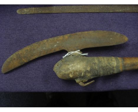 An African tribal iron headed axe:, the slightly curved blade on a natural wooden shaft with hide covered head, 84cm long.