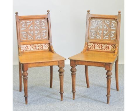 A pair of 19th century light oak hall chairs, with fret carved and tiled backs, on fluted legs 