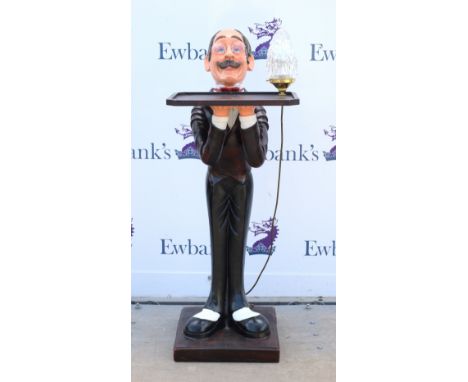 Novelty dumb waiter, modelled as a male figure carrying a tray and lamp, 109 cm high        Lamp slightly loose. Only minor s