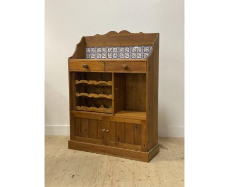 A late 20th century pine kitchen cabinet, the raised back inset with tiles and two drawers, above a wine rack and open shelf 