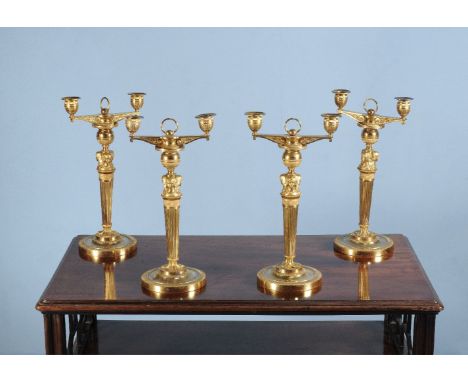 A set of four Empire ormolu twin light candelabra, early 19th century, each with urn sockets on scroll cast horizontal arms b