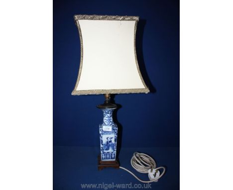 A Chinese blue/white table Lamp on wooden plinth with cream shade with gold braiding.