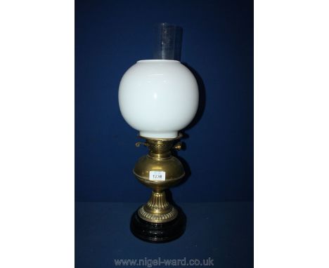A Brass paraffin Lamp with black plinth and spherical white shade.