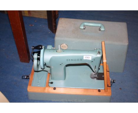 A Singer hand Sewing machine in case in a light green colour.