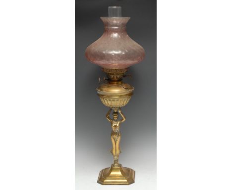 An Art Nouveau brass figural oil lamp, sinuous caryatid surmounted by an urnular reservoir and glass shade, canted square bas