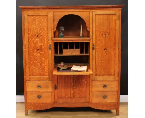 An Arts &amp; Crafts oak and marquetry secretaire side cabinet, outswept dentil cornice above a niche and a fall front door, 