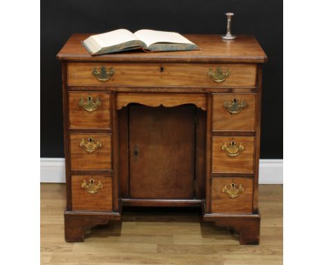 A 19th century mahogany kneehole desk, rectangular top with reentrant foreangles above a long drawer and shaped apron drawer,