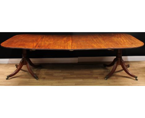 A Regency mahogany twin-pillar extending dining table, rounded rectangular top with reeded edge and two additional leaves, tu