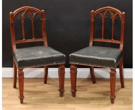 A pair of late Victorian Gothic Revival oak hall chairs, each with an architectural back, stuffed-over seat, quatrefoil cappe