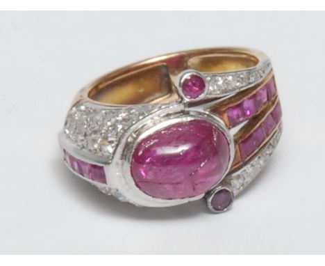 An Art Deco design ruby, diamond and yellow gold coloured metal ring, the geometric 'buckle' design set with an oval cabochon