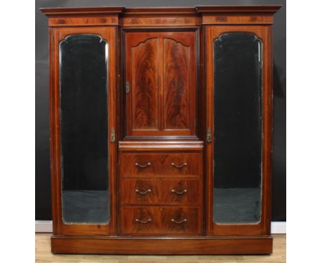 An Edwardian flame mahogany compactum wardrobe, outswept inverted break-centre cornice, the centre with a panel door enclosin