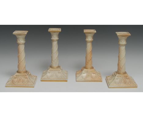 A pair of Royal Worcester table candlesticks, in relief with husk swags, the spreading square base, with oval ram's head and 