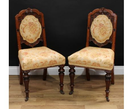 A pair of late Victorian oak hall chairs, each with a shaped cresting rail carved and applied with flowerhead bosses, the bac