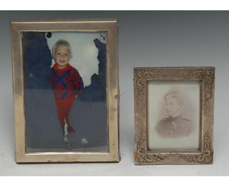 A Victorian silver rectangular easel photograph frame, embossed to the angles with flowers and leafy scrolls, containing a mi