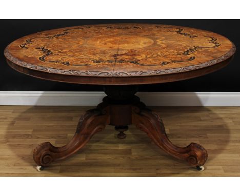 A Victorian walnut and marquetry centre table, circular top with foliate carved edge, profusely inlaid in specimen timbers wi