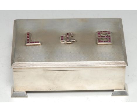 An Art Deco style ruby mounted silver rectangular cigarette box, the hinged cover set with forty five square-cut stones, on a