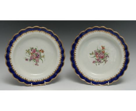 A pair of Worcester shaped circular plates, painted with bouquets of roses, poppies and other country flowers, bordered with 