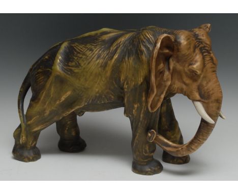A large Continental model, possibly Royal Dux,  of an African elephant, in burnished gilt and green, trunk down, 26cm high, c