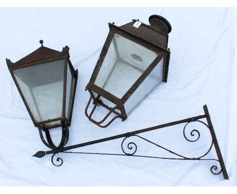 Antique painted metal street lamp, tapered form with glazed sides projecting on scrolling bracket, together with a similar la
