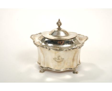 Edwardian silver tea caddy of flared faceted form with scroll borders, engraved armorial crest and hinged domed cover on four