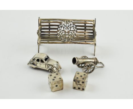 A collection of miniature silver items to include a pair of dice, a Victorian style bench, 6cm long, a cannon (test as silver